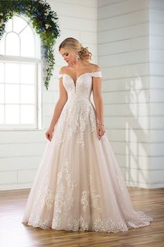 a woman in a wedding dress standing on a wooden floor with her hands behind her back