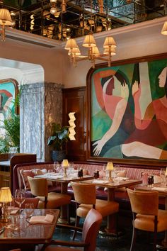 a dining room with tables, chairs and paintings on the wall behind them in an art deco style