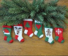 three christmas stockings hanging from a tree on a wooden floor with pine needles and snowflakes