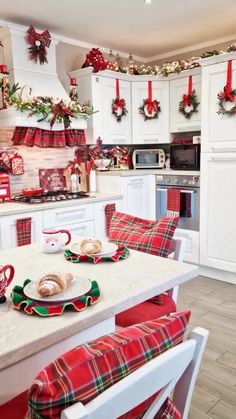 a kitchen decorated for christmas with red and green plaid decorations on the walls, white cabinets and countertops