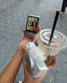 a person taking a photo with their cell phone while holding up a cup of coffee