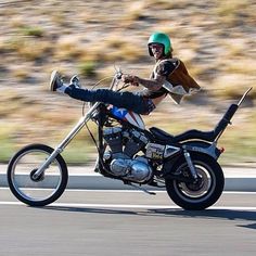 a man riding on the back of a motorcycle down a road