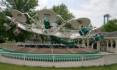 an amusement park with several rides on the top and one in the middle, surrounded by green grass