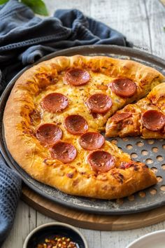 two slices of pepperoni pizza sitting on top of a metal pan next to bowls and spoons