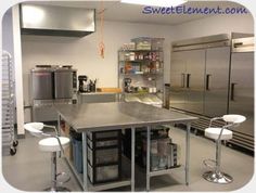 an industrial kitchen with stainless steel appliances and stools in the middle of the room