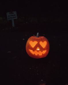 an illuminated pumpkin with hearts carved into it