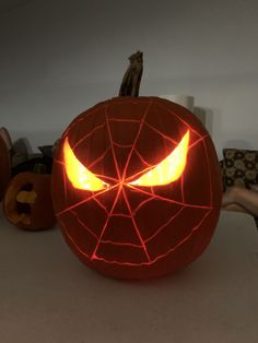 a pumpkin carved to look like a spiderman's face with its eyes glowing