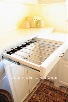 an open drawer on the side of a white kitchen cabinet with flowers in vases