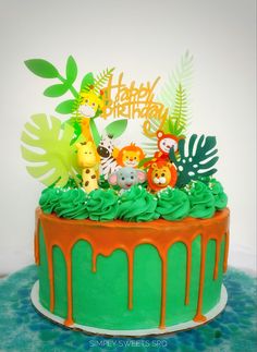 a birthday cake with green frosting and jungle animals on top is decorated with orange icing