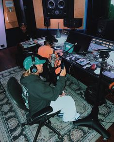 two people sitting at a table with headphones in front of microphones and recording equipment