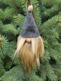 an ornament hanging from a tree with long blonde hair and a gnome's hat on it