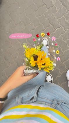 a person sitting on the ground with flowers in their lap