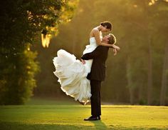 a bride and groom are dancing on the golf course in front of trees at sunset