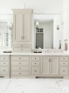 a large bathroom with white cabinets and marble counter tops