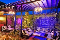 an outdoor seating area is lit up with purple lighting and potted plants in the background