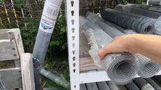 a person is holding some kind of wire mesh in front of a fenced area