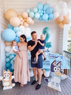 a man, woman and child standing in front of a table with balloons