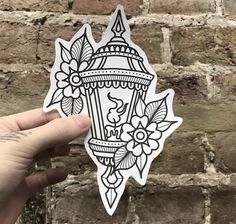 a hand holding up a sticker with an image of a light fixture on it