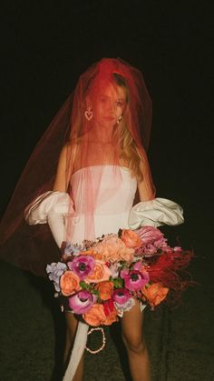 a woman in a white dress and veil with flowers on her head is holding a bouquet