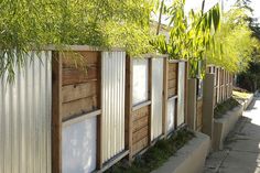 a fence made out of wooden boards with plants growing on the top and bottom panels