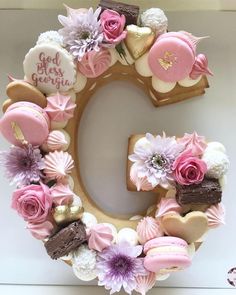 the letter c is decorated with pink and white flowers, cookies, and other items