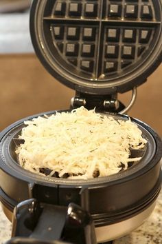 a waffle iron with shredded cheese on top