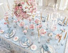 the table is set with pink and white flowers in vases, silverware, and plates