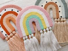 four different colored rugs with tassels on them and one has a rainbow in the middle