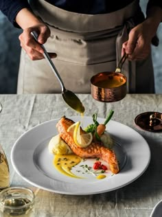 a chef is preparing food on a plate with spoons and utensils in his hands