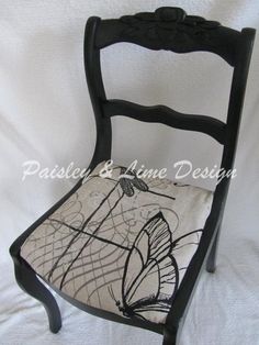 a black chair with a butterfly on the back and white fabric seat pad under it