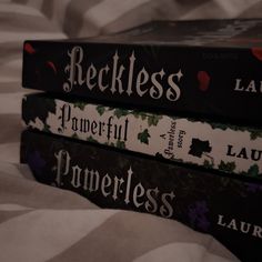 three books stacked on top of each other in front of a white and black bed