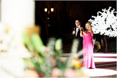 a man and woman standing next to each other in front of a white flower arrangement