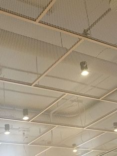 the ceiling in an office building has mesh coverings on it and lights hanging from the ceiling