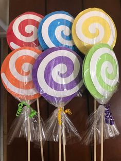 colorful lollipops wrapped in plastic wrappers are on sticks with ribbons around them