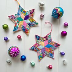 colorful christmas ornaments are laying on a white surface with one star hanging from it's side