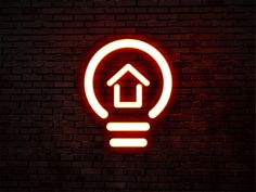 a neon light bulb with a house inside it on a brick wall in the dark