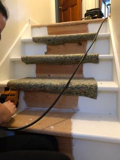 a woman is using a power drill to clean the carpet on the stairs in her home