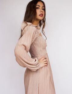 Our Arcadia dress is a glistening rose champagne mini. It has a shirred bodice in a bustier design, long sleeves with ruffles on the shoulder for a very feminine take on a heart neckline, a square back and a light pleated skirt. Runs true to size.Has a good amount of stretch. S= 0-4-; M= 6-8; L= 10-12 Model is 5'6 wearing size S. CARE This is a cruelty free piece made carefully and ethically for Blue District, preserve its life by reading and following the tag guidelines. Tip: When in doubt, air Long Sleeve Mini Dress With Ruched Bodice For Brunch, Feminine Long Sleeve Mini Dress With Fitted Bodice, Chic Beige Mini Dress With Smocked Bodice, Elegant Pink Mini Dress With Smocked Back, Long Sleeve Dress With Smocked Bodice For Date Night, Flirty Long Sleeve Dress With Ruched Bodice, Fall Party Mini Dress With Smocked Back, Fall Mini Dress With Smocked Back For Parties, Elegant Pink Mini Dress With Smocked Bodice