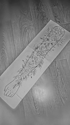 a piece of paper with flowers on it sitting on a wooden floor next to a pair of scissors