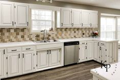 a kitchen with white cabinets and wood floors