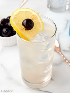 a tall glass filled with lemonade and garnished with cherries