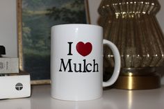 a coffee mug with the word i love mulch on it next to a camera