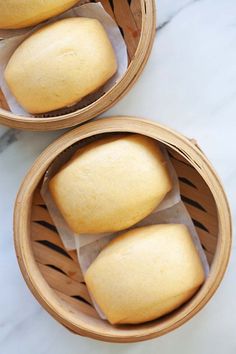 two baskets filled with bread sitting on top of a white counter next to each other