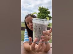 a girl holding up a cup filled with sand