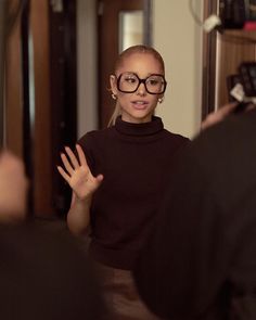 a woman wearing glasses is standing in front of a mirror with her hands out to the side