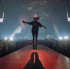 a person walking down a runway with their arms outstretched in front of the crowd at a concert