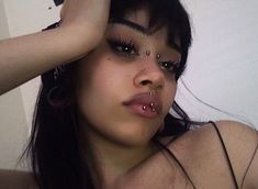 a woman with piercings on her nose is posing in front of a mirror and looking at the camera