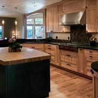 a large kitchen with wooden cabinets and black counter tops, along with a center island