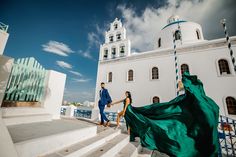 a man and woman holding hands while walking up some steps in front of a building