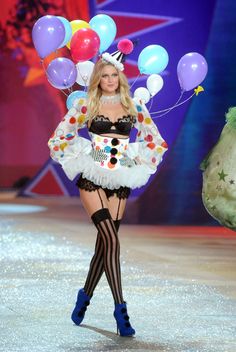 a model walks down the runway in a costume with balloons on her head and stockings